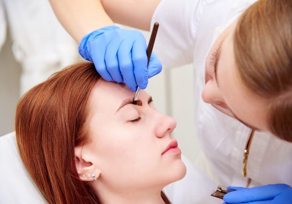 Young woman on eyebrow correction in cosmetology clinic.